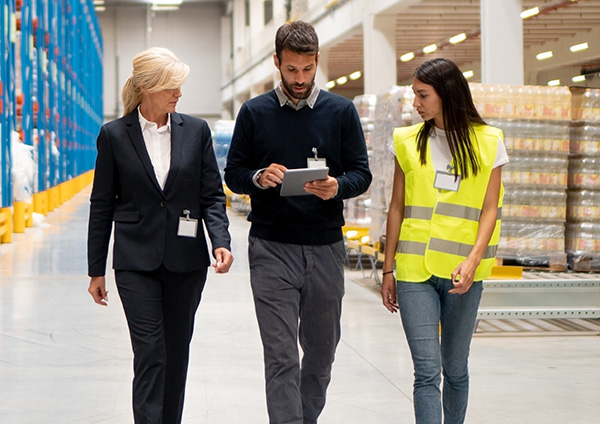 Three people walking through a warehouse