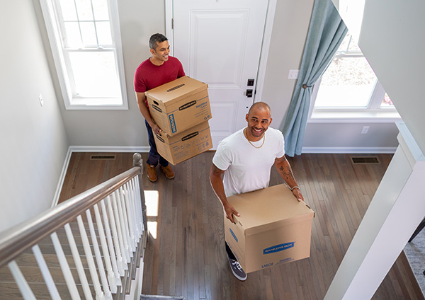 two friends moving boxes into a new home