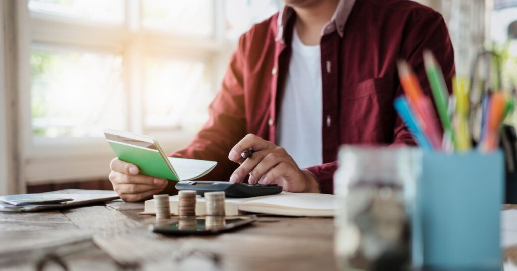 Man sitting at desk balancing his checkbook and managing his money.