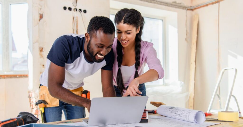 Couple in the middle of a home renovation looking at a laptop.