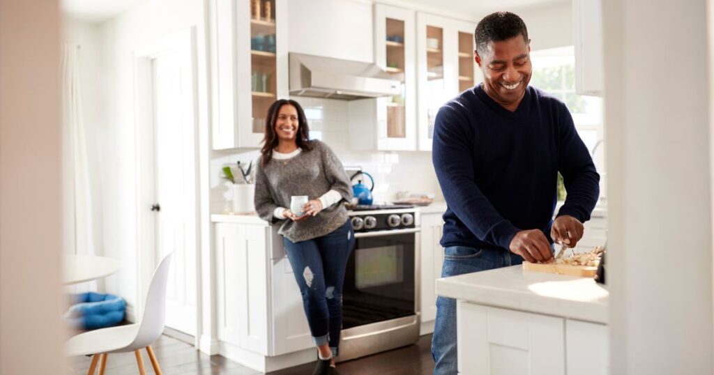 Man and woman couple in kitchen cooking and smiling.