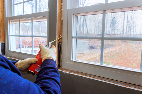 Person applying spray insulation for new windows