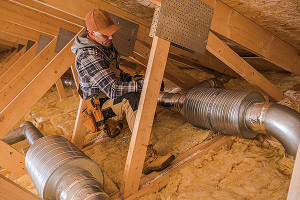 Person installing HVAC ductwork in attic