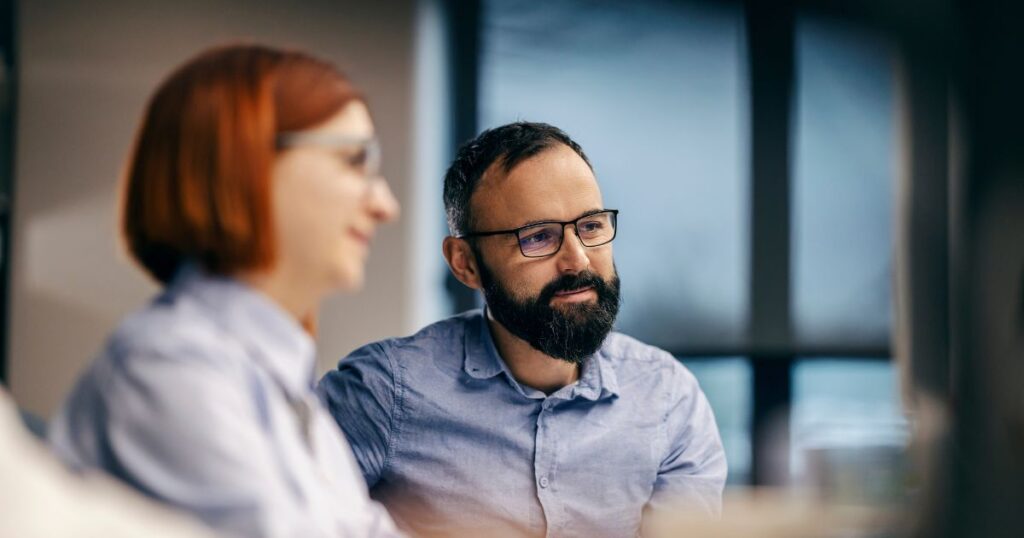Man with glasses sitting in a meeting with colleague