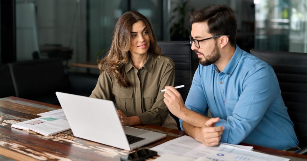 Woman and man coworkers having a meeting and viewing a laptop.