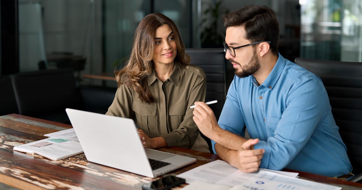 Woman and man coworkers having a meeting and viewing a laptop.