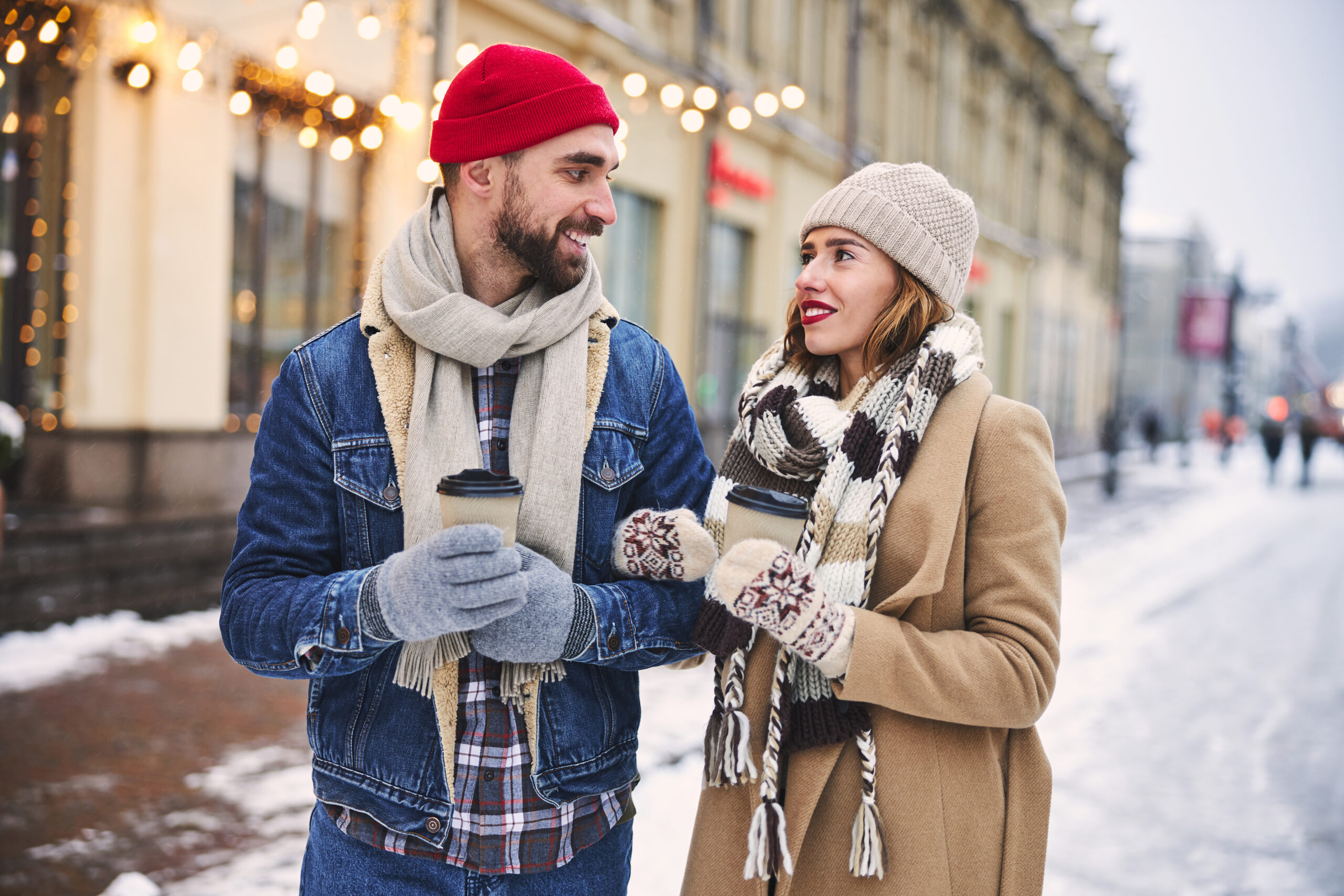 Woman and man couple drinking hot beverages outside in winter.