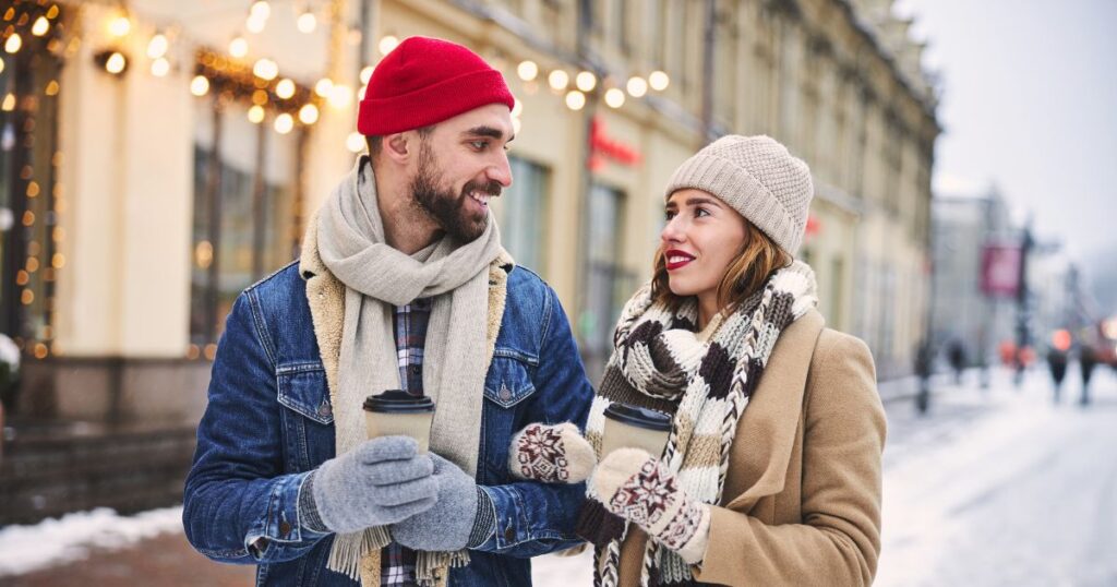 Woman and man couple drinking hot beverages outside in winter.