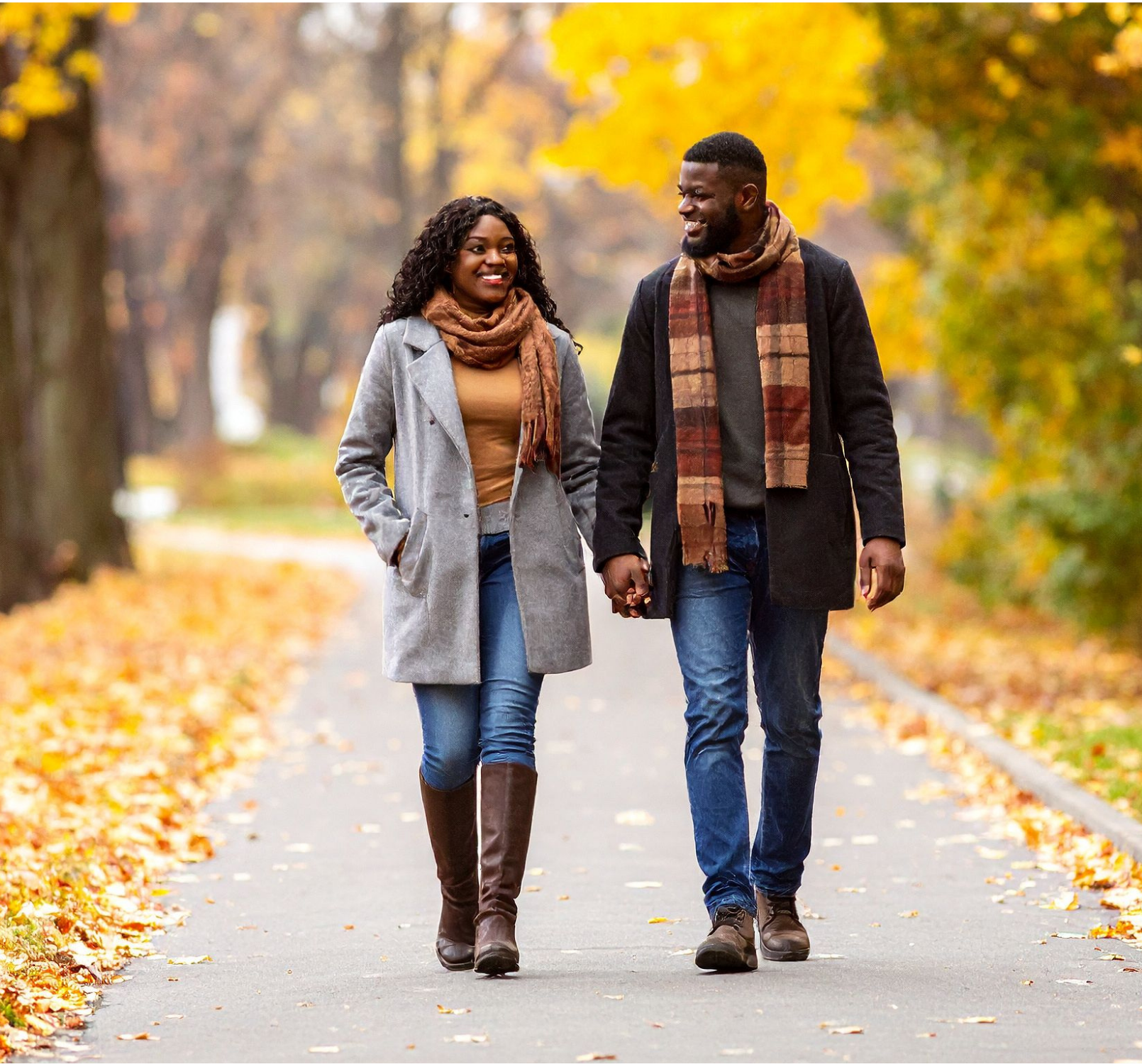man and woman walking hand-in-hand through fall scenery