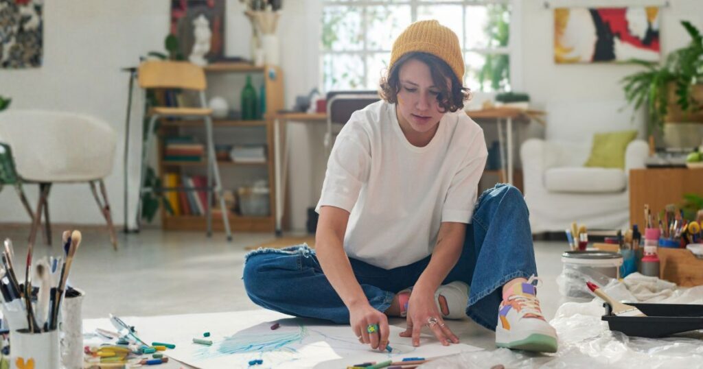 Young woman artist sitting on the floor sketching.