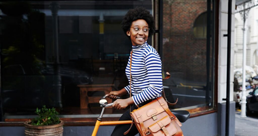 Young woman smiling while walking with her bicycle.