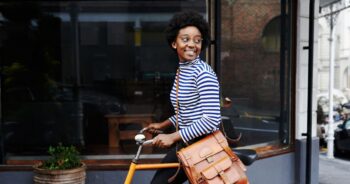 Young woman smiling while walking with her bicycle.